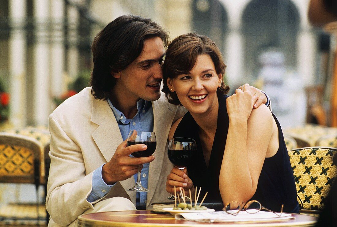 Young couple at café table with red wine