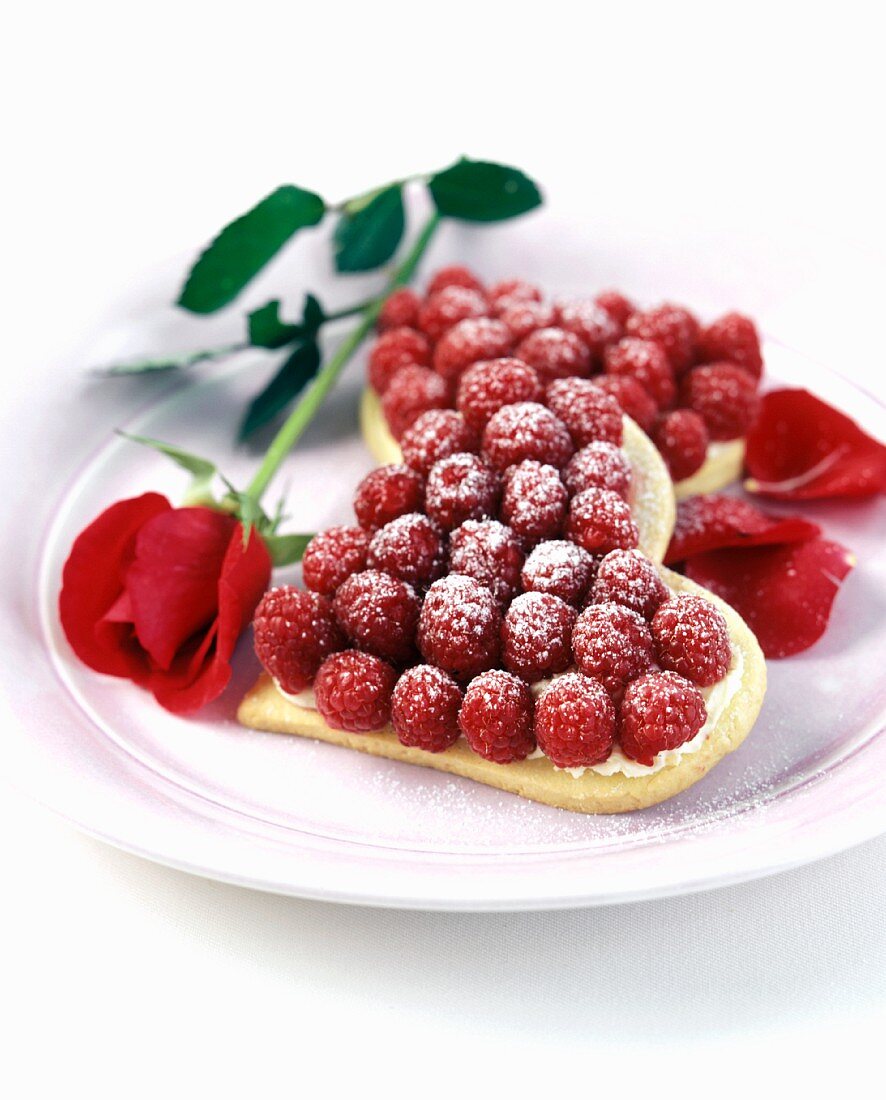 Mürbteigherz mit Himbeeren auf Teller, Deko: Rose