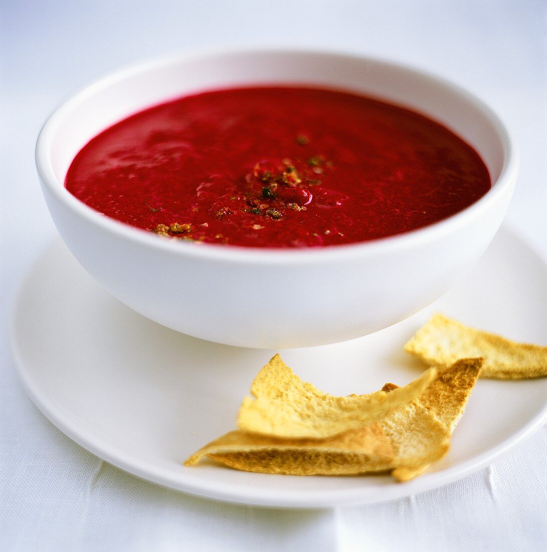 Beetroot soup in a bowl, with taco crisps