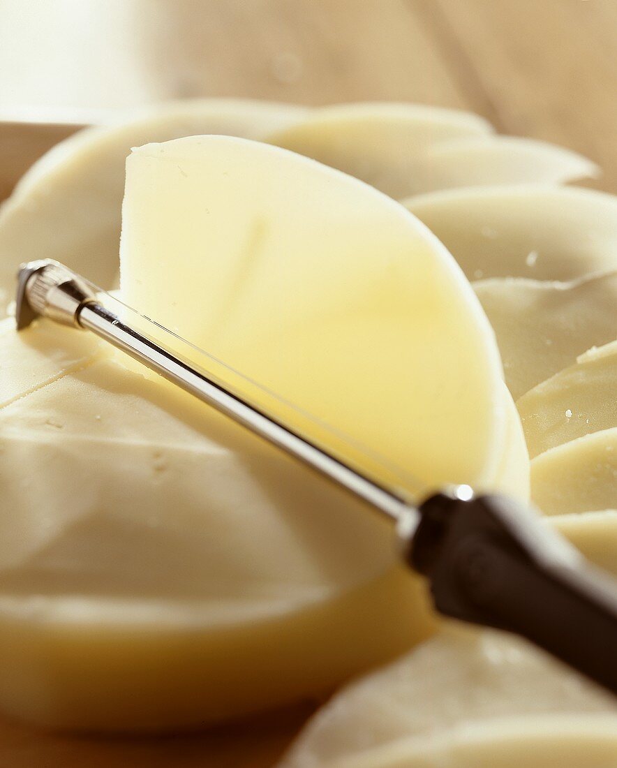 Cheese cutter cutting a slice from a Provolone Valpadana