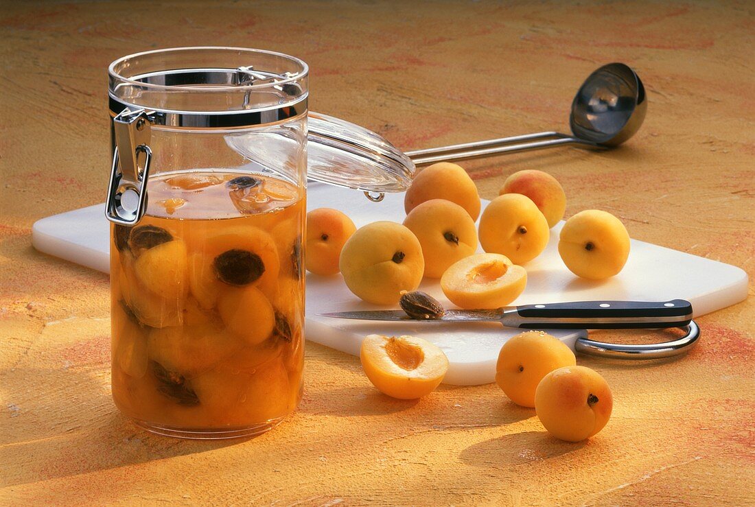 Selbst gemachter Aprikosengeist im Glas und frische Aprikosen
