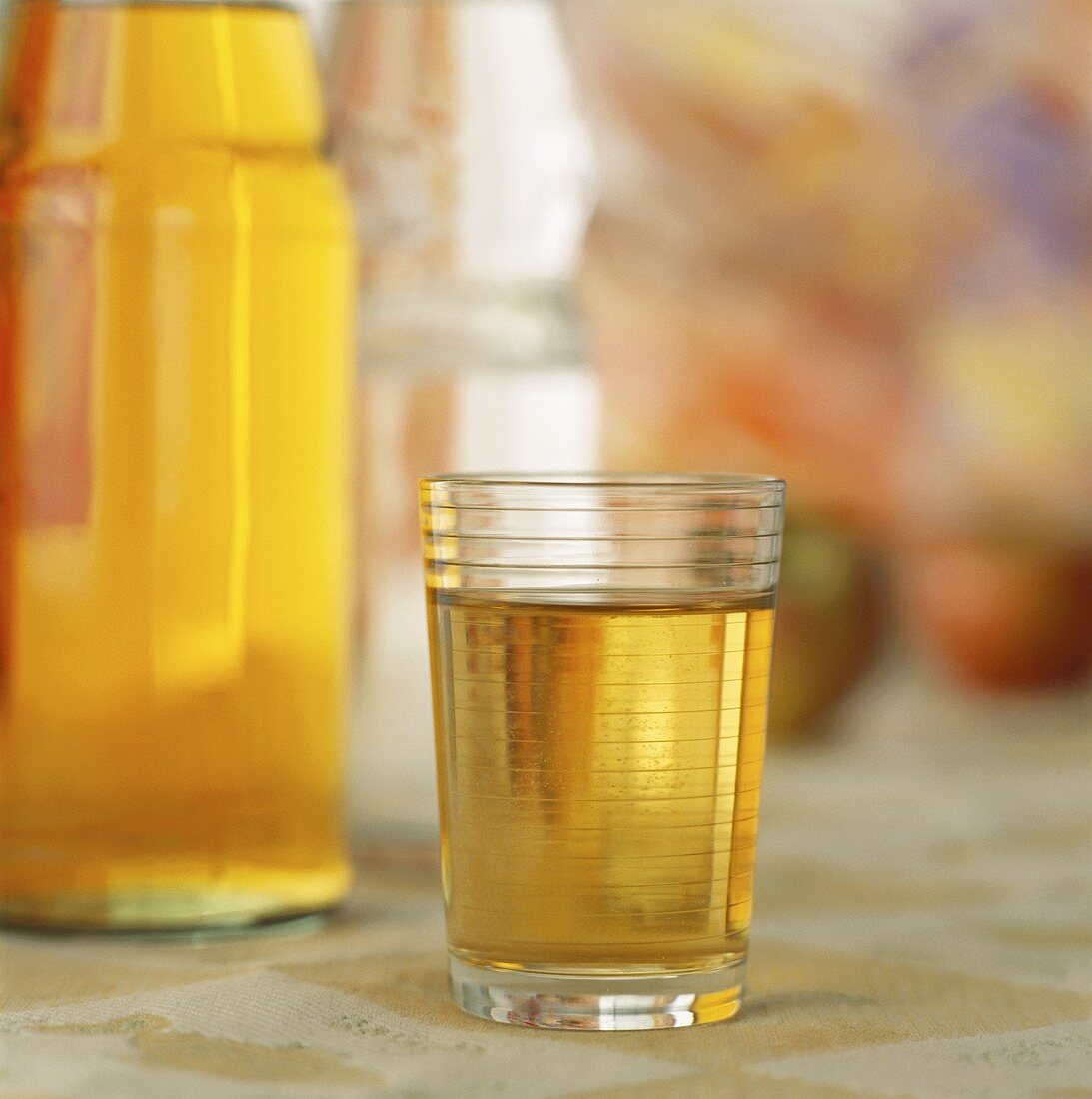 Glas Apfelschorle vor Apfelsaft- und Mineralwasserflasche
