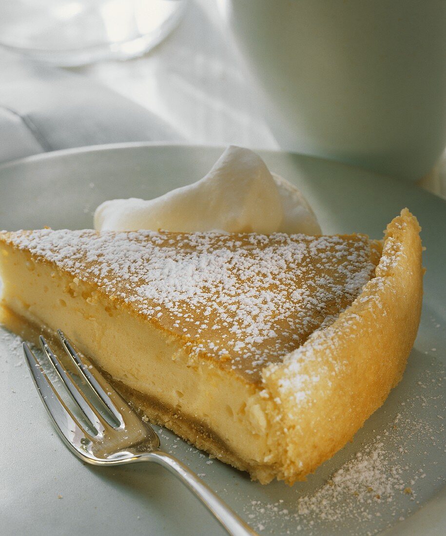 Ein Stück Käsekuchen mit Sahne auf Teller