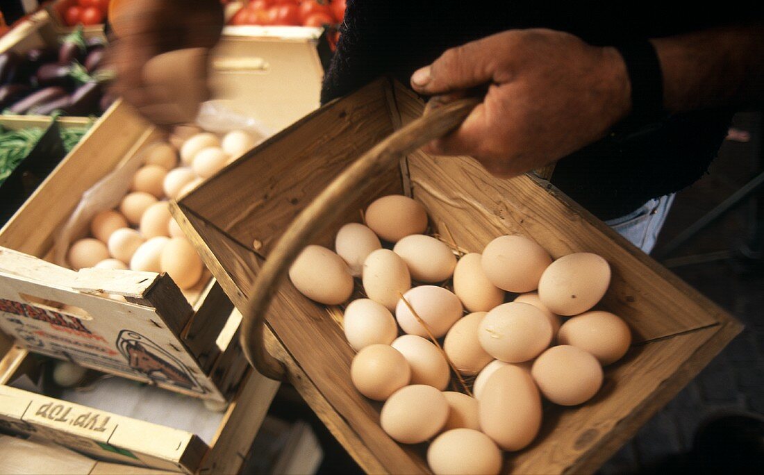 Mann legt Eier in einen Korb auf einem Markt