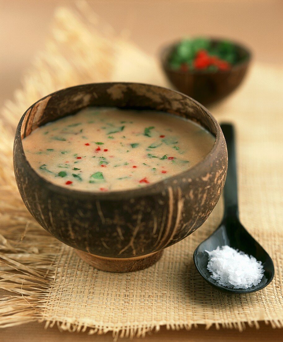 Tamarind & coconut soup with coriander & mint in wooden bowl