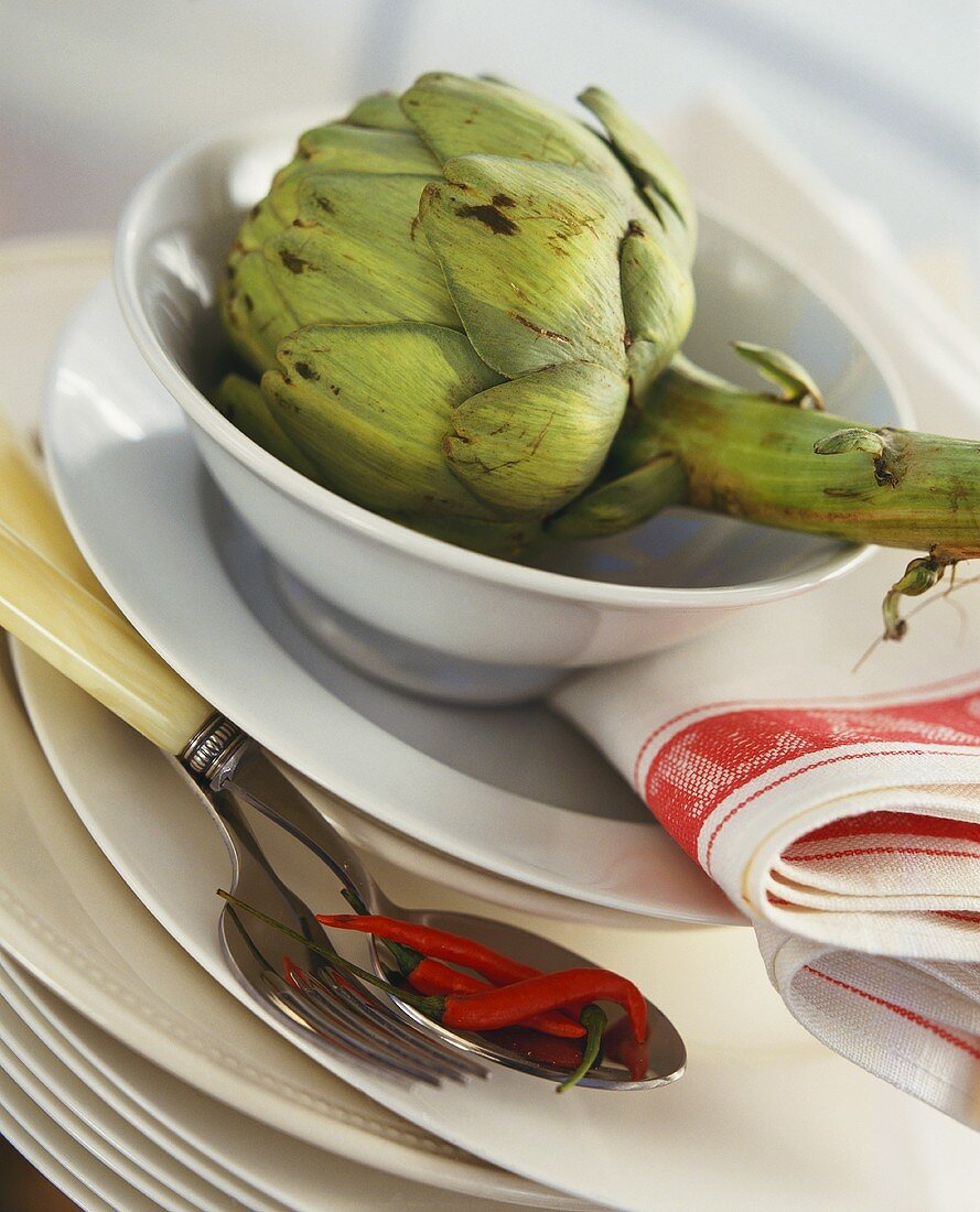 Artichoke in bowl and chili peppers on spoon