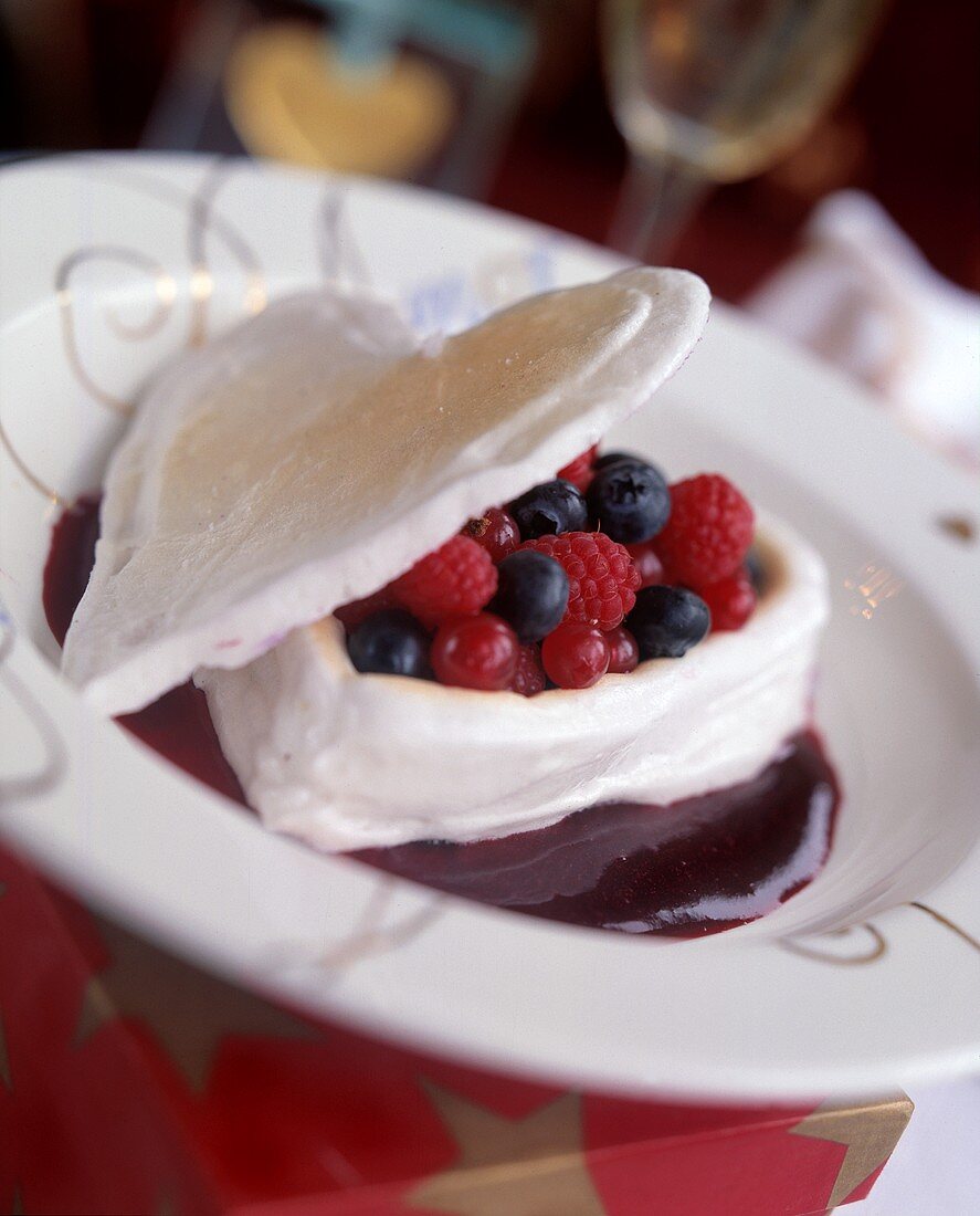 Meringuenherz mit Beeren gefüllt, dazu Beerensauce