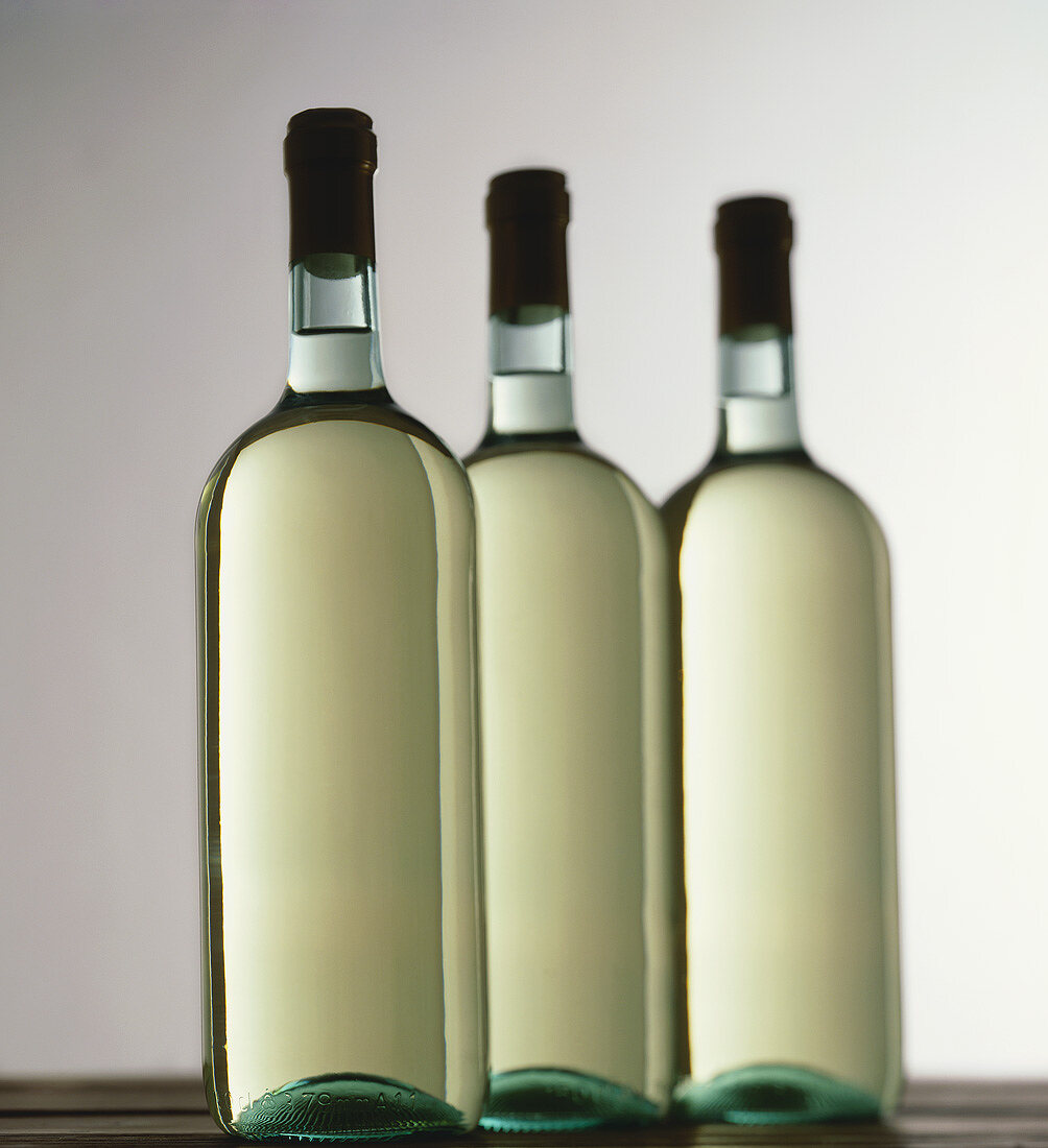 Drei Flaschen Weißwein stehen in einer Reihe