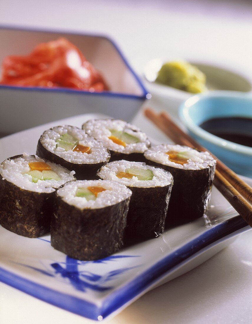 Sushi auf Teller, dahinter verschiedene Saucen