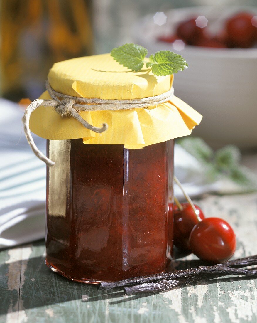 Kirschmarmelade im Einmachglas, daneben frische Kirschen