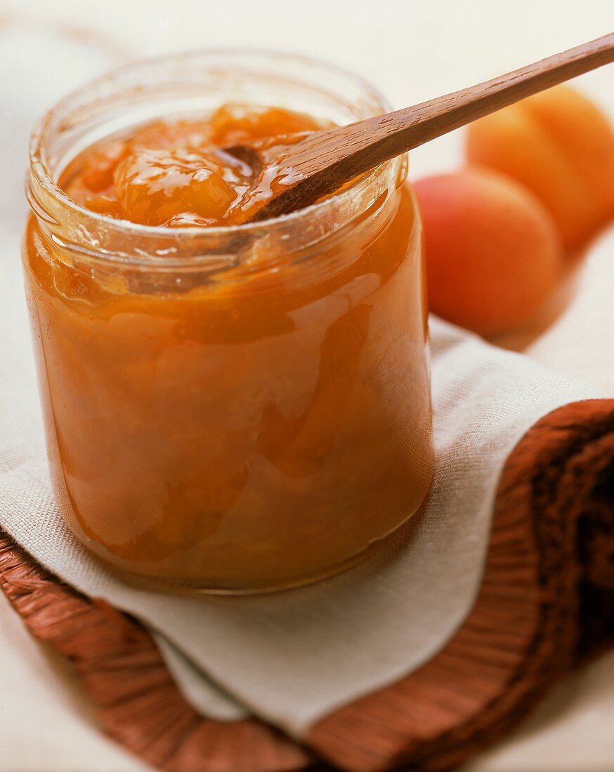 Selbstgemachte Aprikosenmarmelade und Holzlöffel im Glas