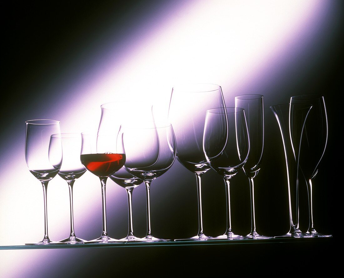 Leere Gläser und ein Glas mit Rotwein