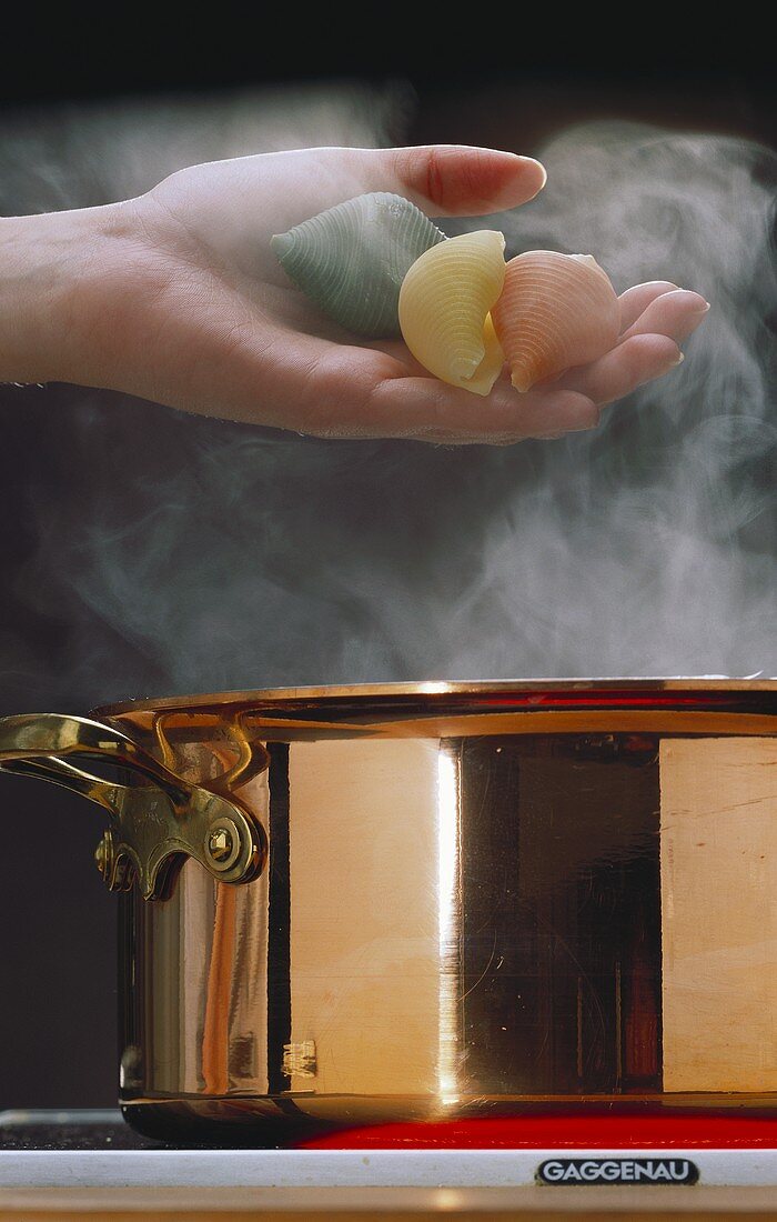 Conchiglioni being dropped into boiling water