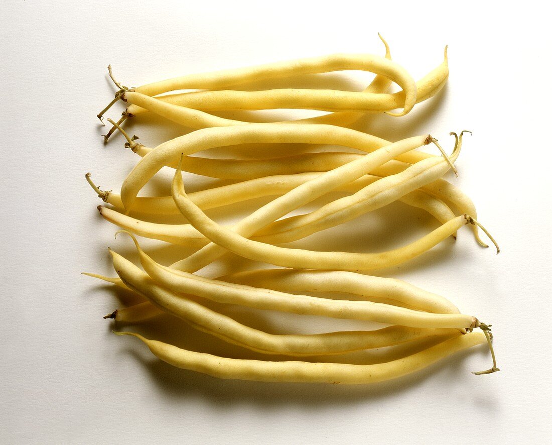 Several wax beans against white background