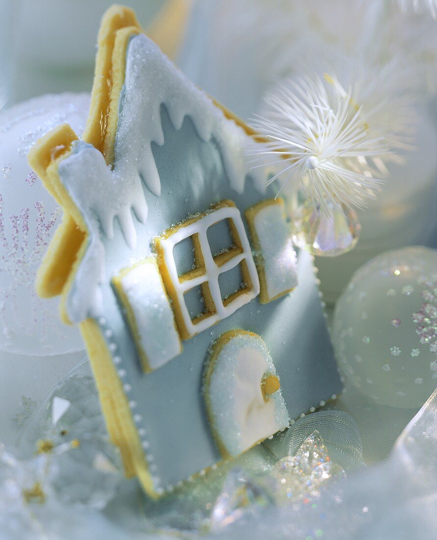 Blaues Häuschen aus Mürbteig, umgeben von Weihnachtskugeln