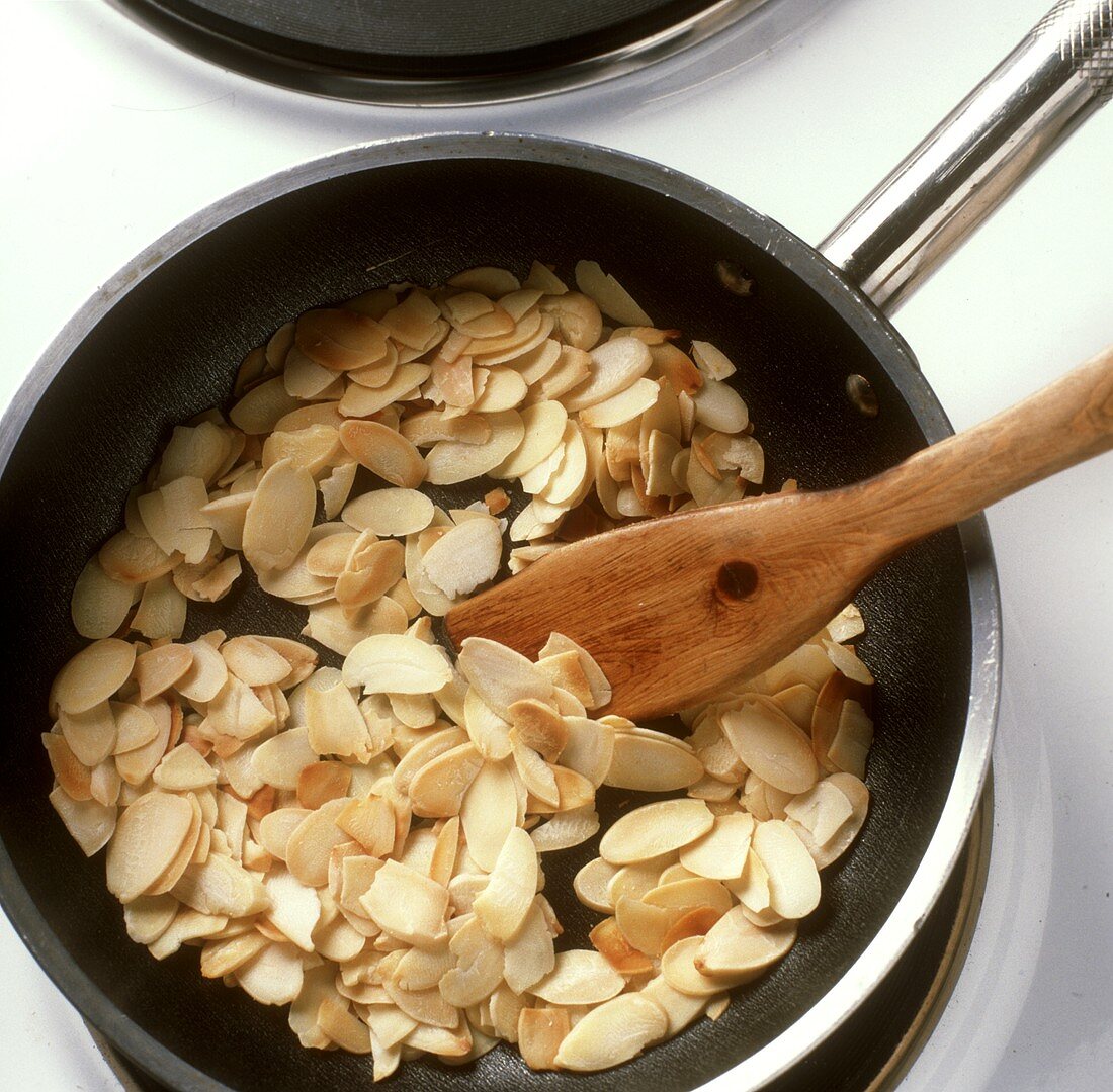 Toasting flaked almonds in a frying pan