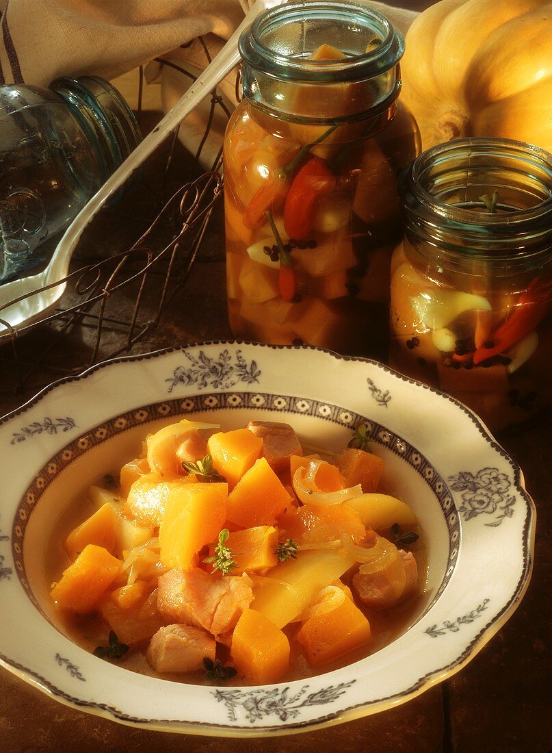 Pumpkin stew with smoked pork rib on plate, decor: jars