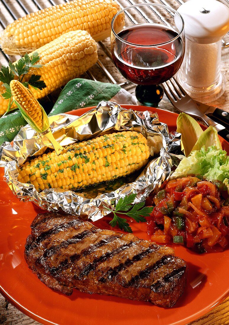 Grilled beef steak and grilled corncobs in aluminium foil