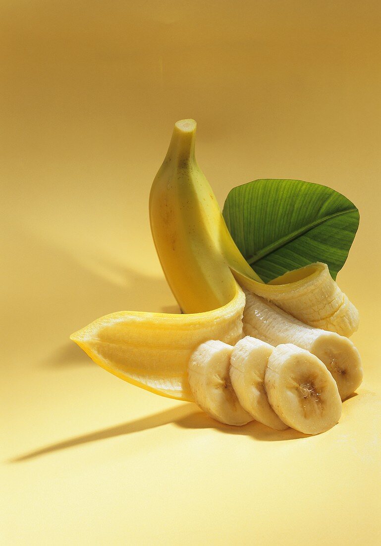 Halb geschälte Banane und Bananenscheiben