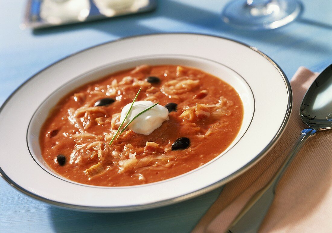 Sauerkraut-Tomaten-Suppe mit schwarzen Oliven und Sahneklecks
