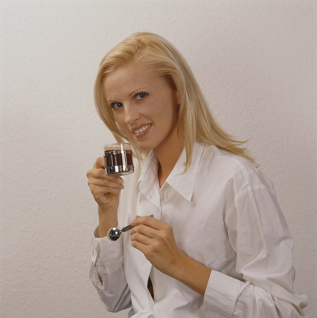 Blonde Frau trinkt Espresso aus einem Glas