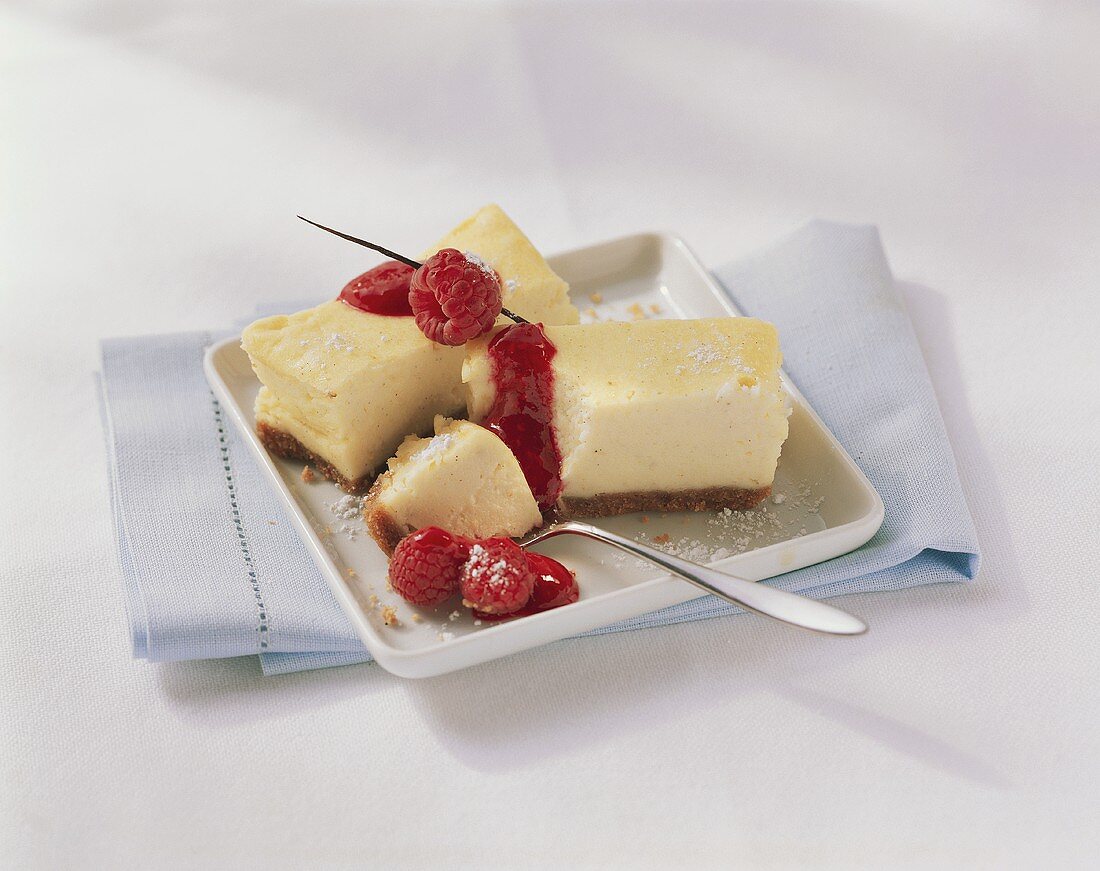 Two pieces of cheesecake with raspberry sauce