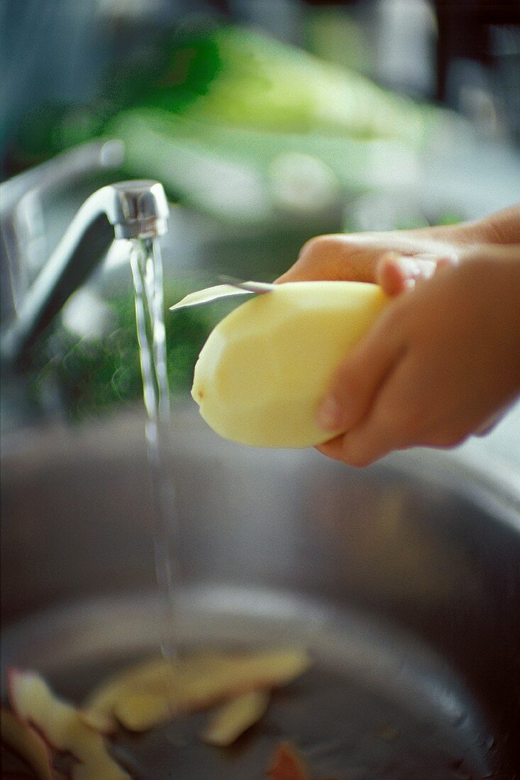 Kartoffel am Waschbecken schälen
