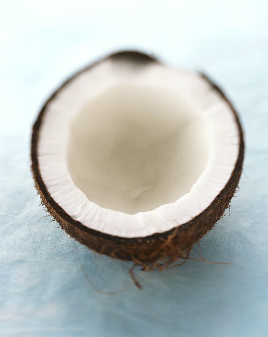 Eine Kokosnusshälfte auf hellblauem Untergrund