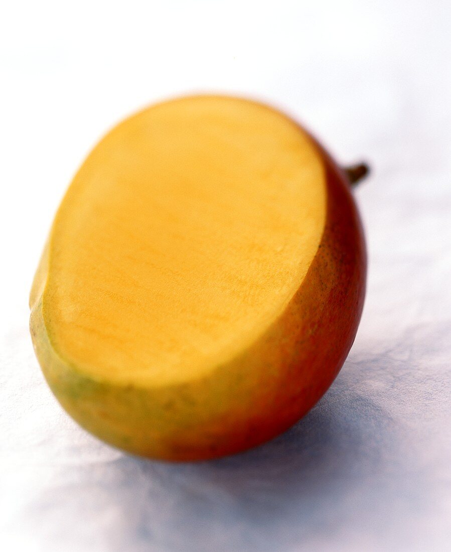 Eine angeschnittene Mango auf hellblauem Untergrund