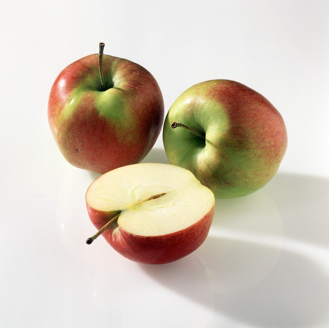 Eine Apfelhälfte und zwei Äpfel der Sorte Jonagold