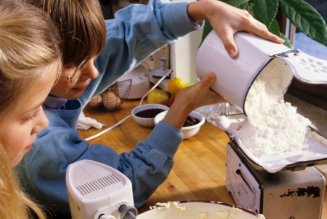Kinder wiegen Mehl für das Backen ab