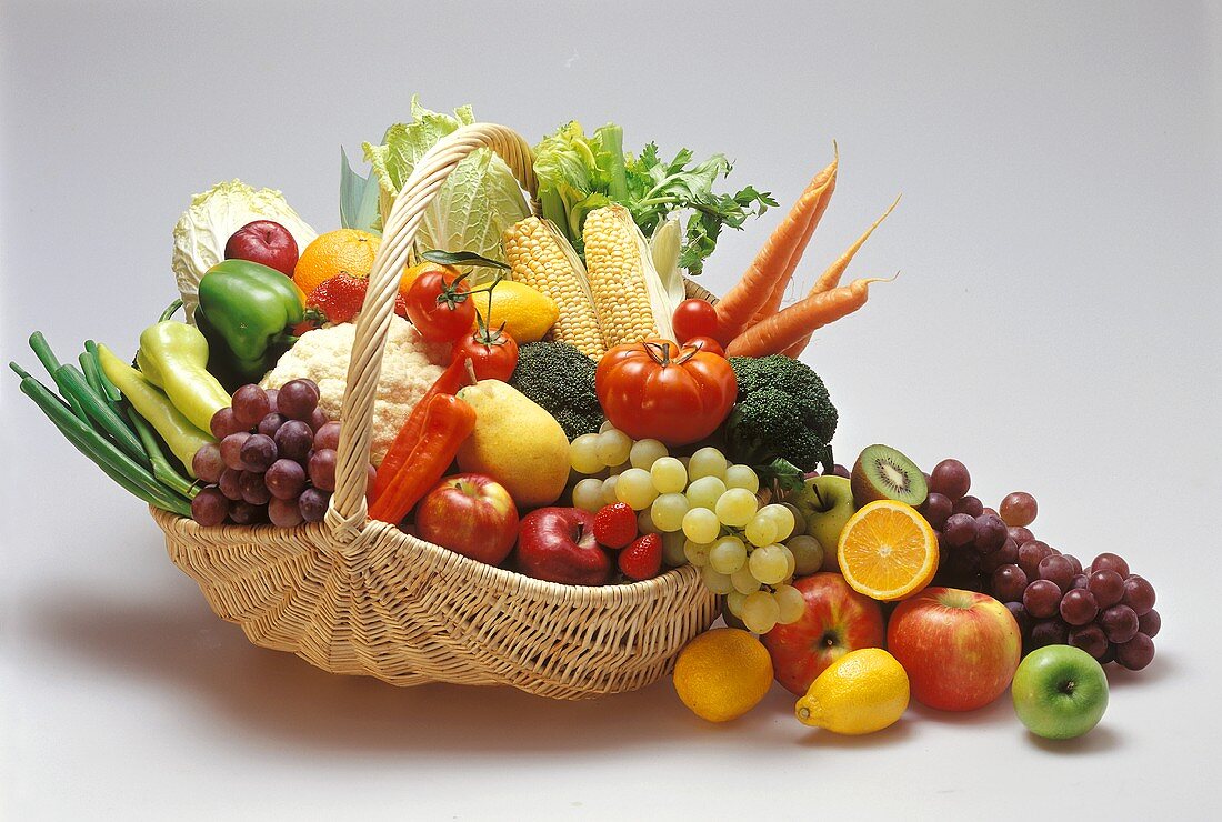 Obst und Gemüse in und neben einem Weidenkorb