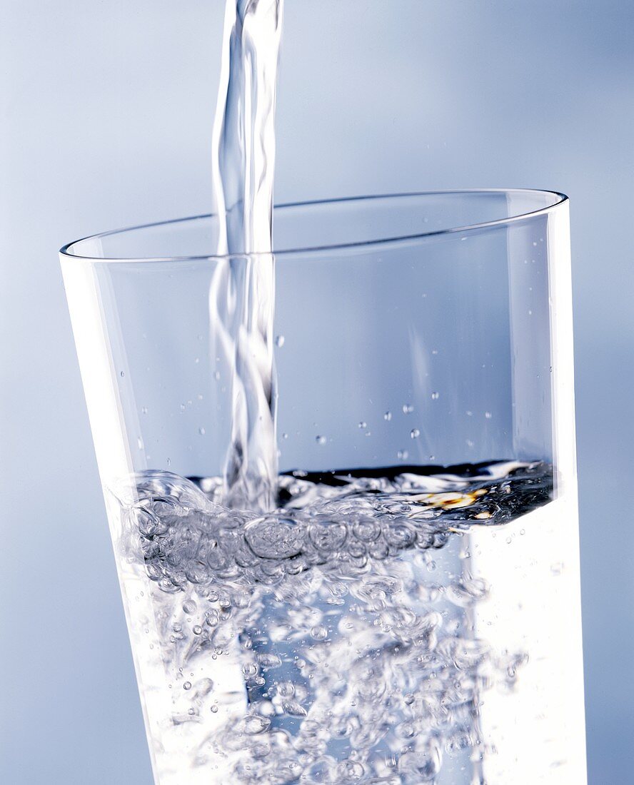 Mineralwasser ins Glas einschenken