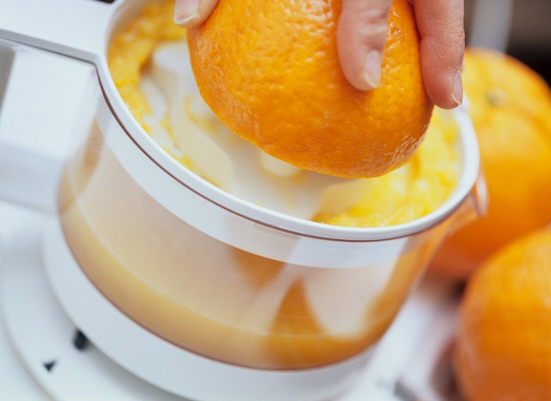 Squeezing an orange with electric citrus squeezer