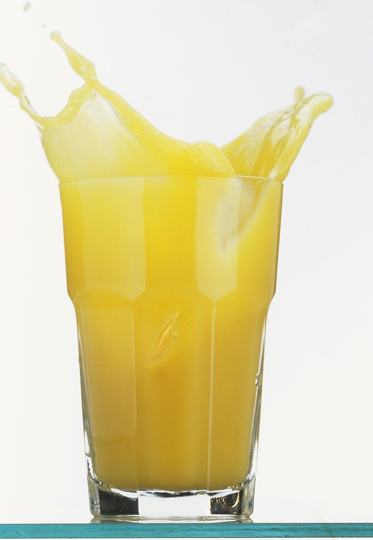 Orangensaft schwappt aus einem Glas