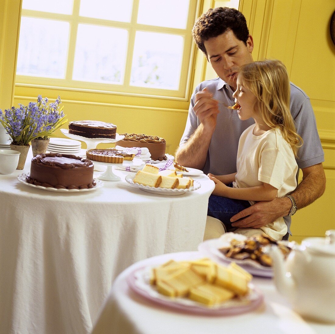 Vater und Tochter essend am Kuchenbuffet