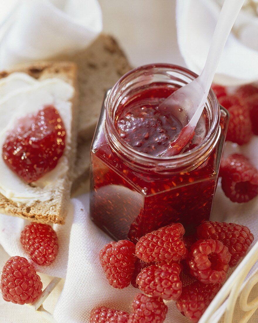 Himbeermarmelade im Glas und auf Brot