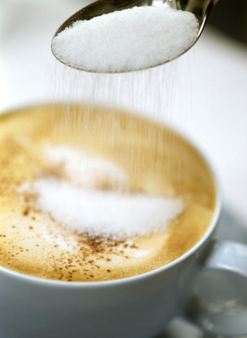 Putting sugar in cappuccino (close-up)