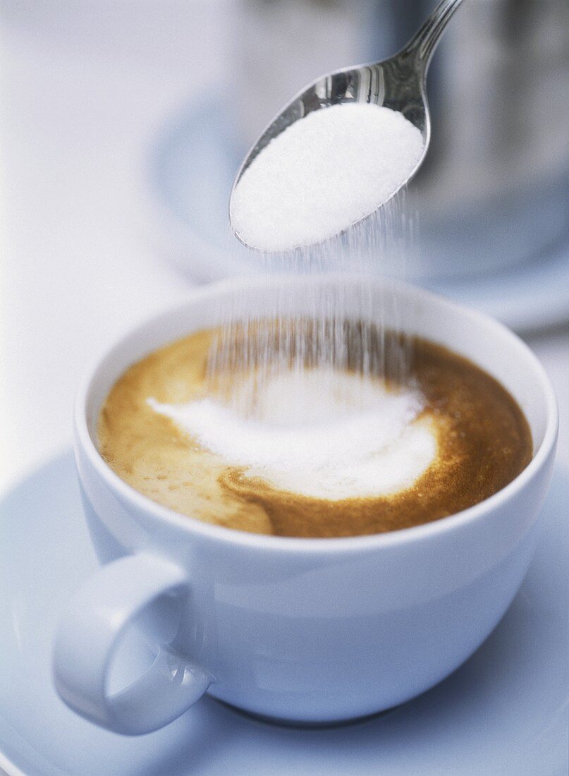 Zucker in Cappuccino geben