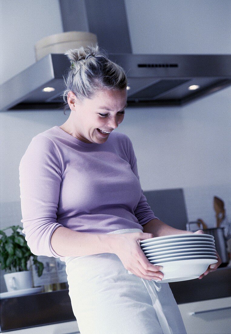 Junge Frau hält einen Stapel Teller