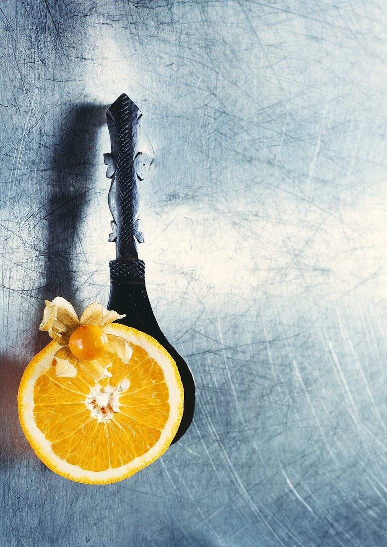 Cape gooseberry with slice of orange on wooden spoon