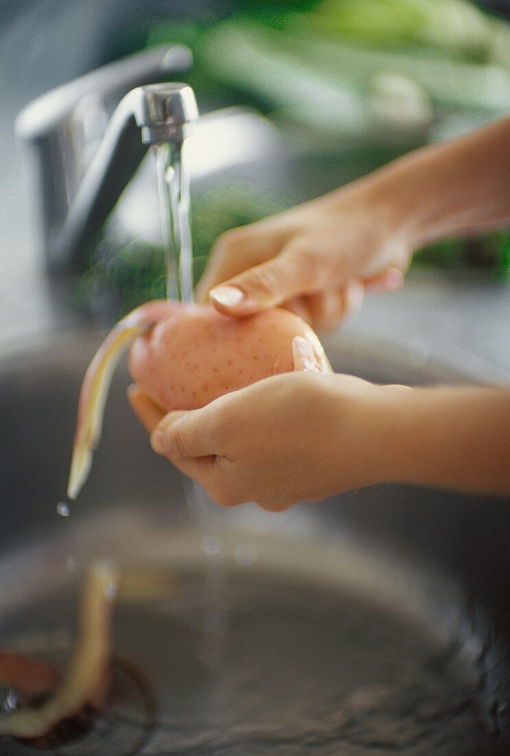 Peeling potato under running water