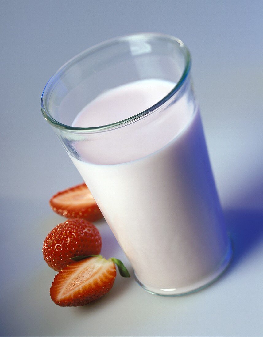 A glass of strawberry milk and fresh strawberries