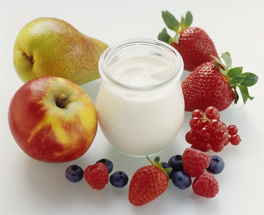 A jar of natural yoghurt surrounded by berries & fruit