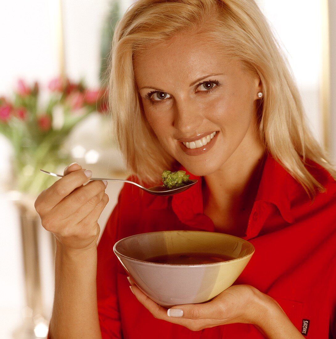 Frau hält ein Schälchen mit Gemüsesuppe