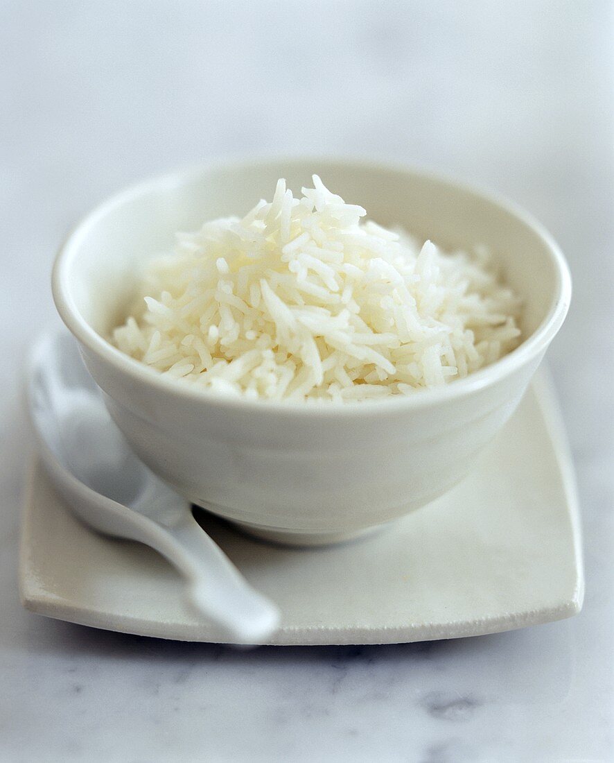 Gekochter Reis in weißem Schälchen mit asiatischem Löffel