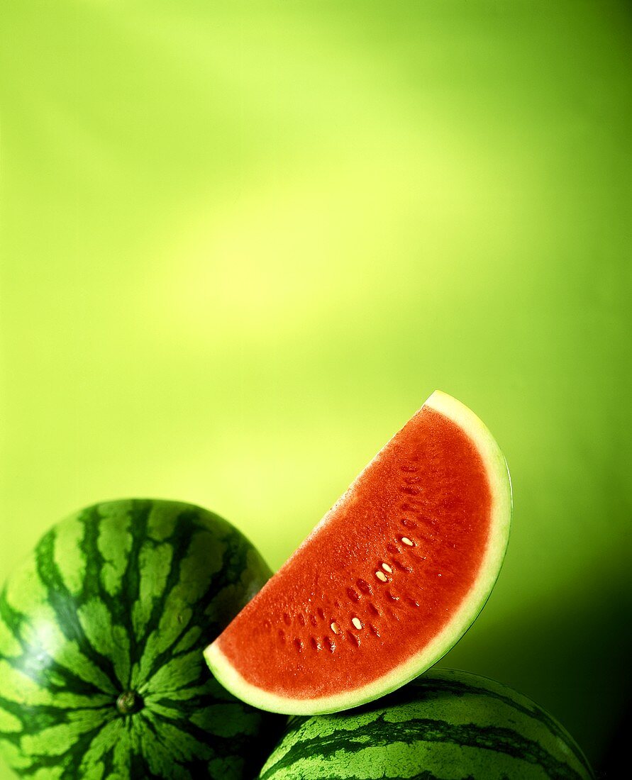 Slice of watermelon and two whole melons