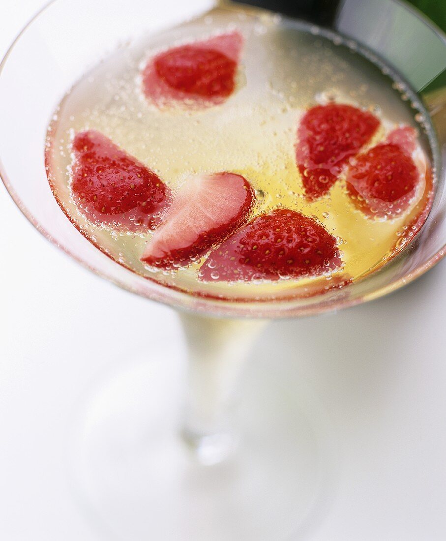 A glass of champagne with pieces of strawberry