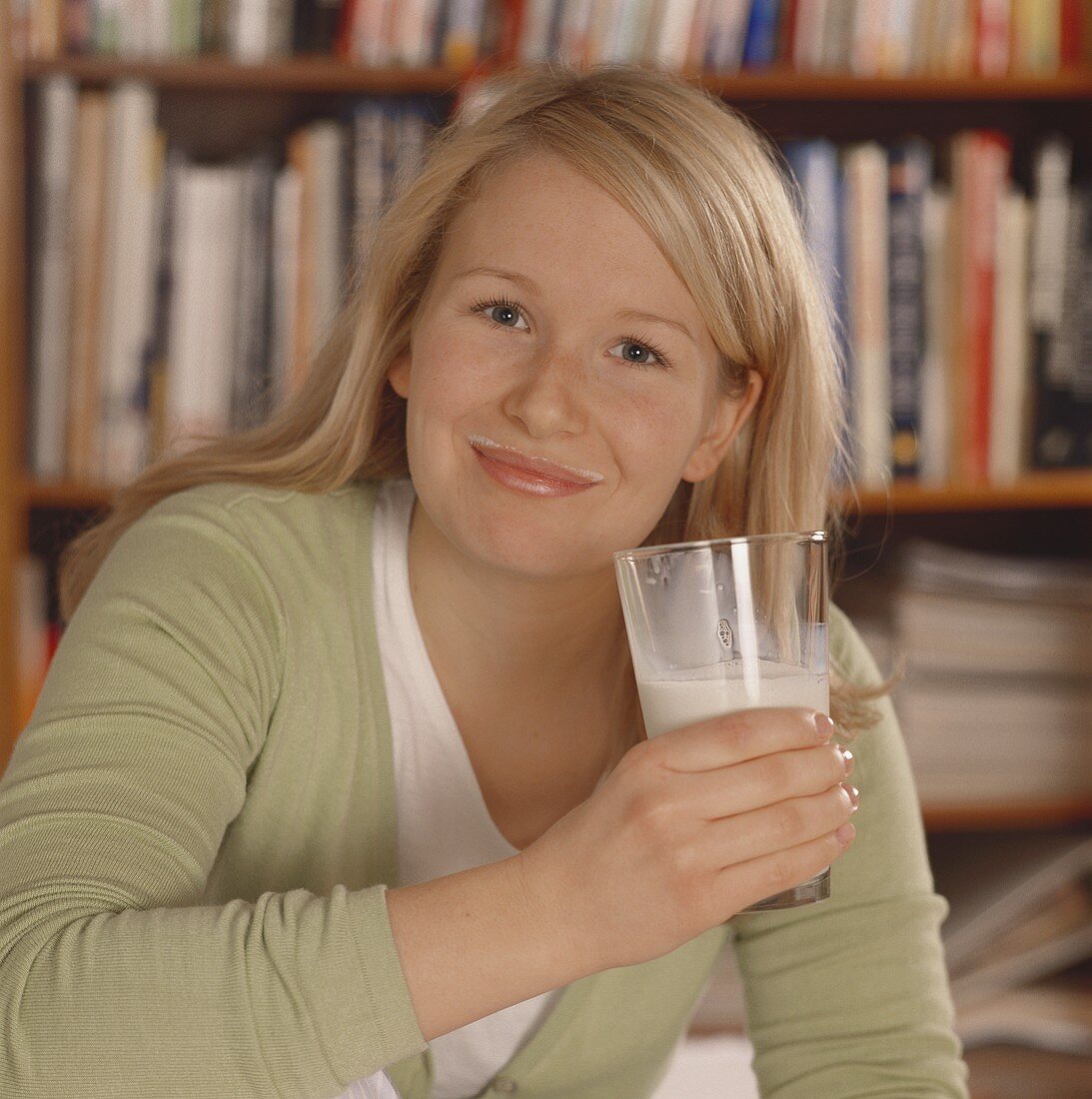 Blonde Frau mit einem Glas Milch & mit Milchrand am Mund
