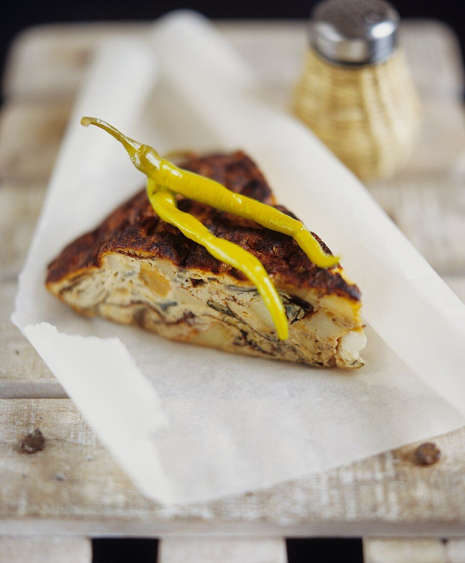 Ein Stück Gemüse-Tortilla mit Schafskäse auf Pergamentpapier